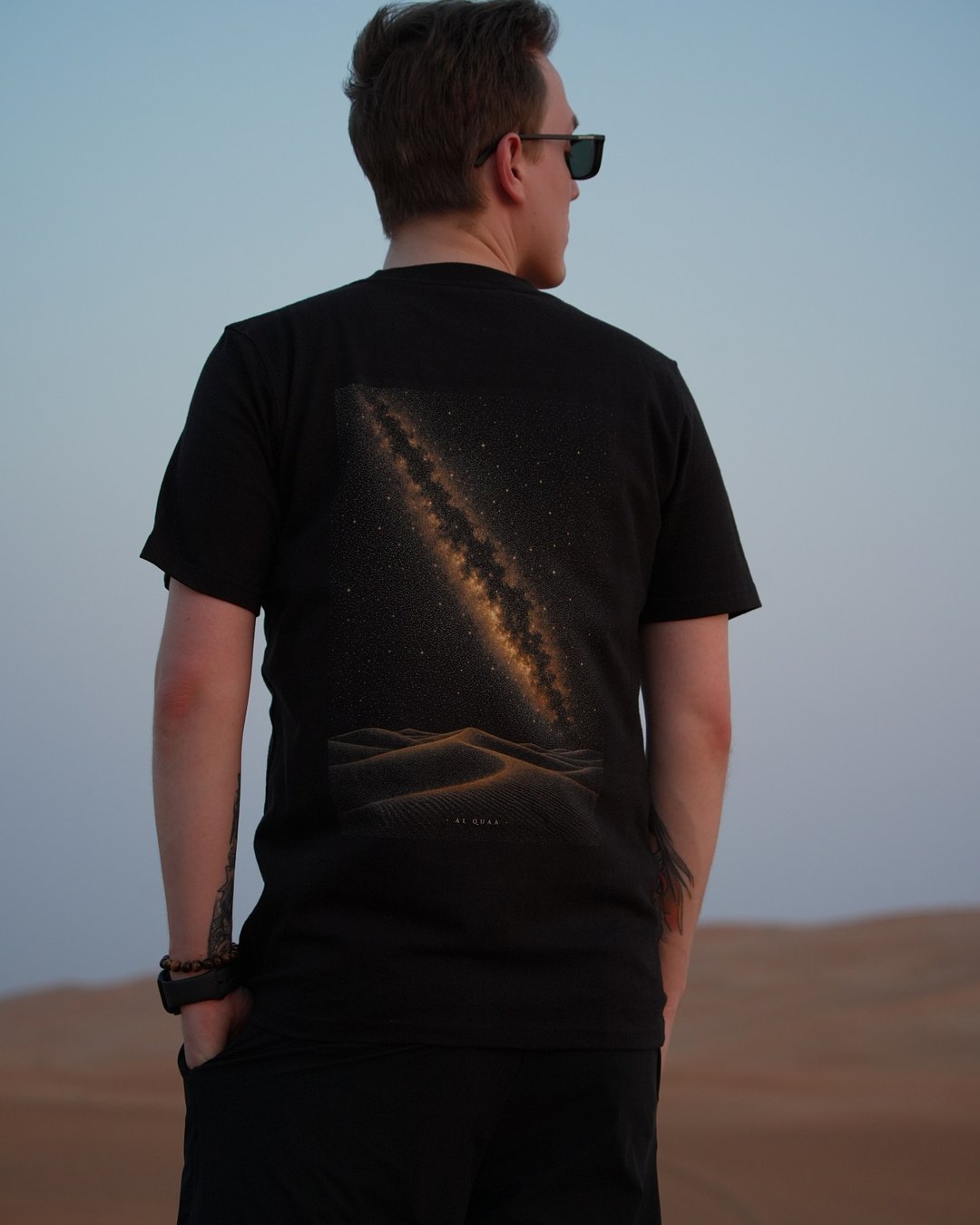 The Al Quaa Galaxy tee worn in the dunes — the printed Milky Way running across the back