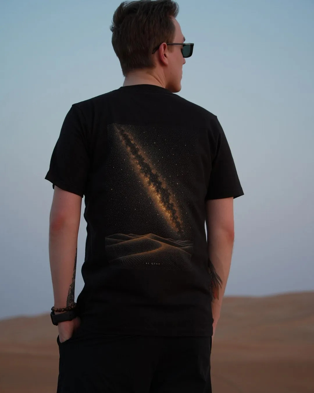 The Al Quaa Galaxy tee worn in the dunes — the printed Milky Way running across the back