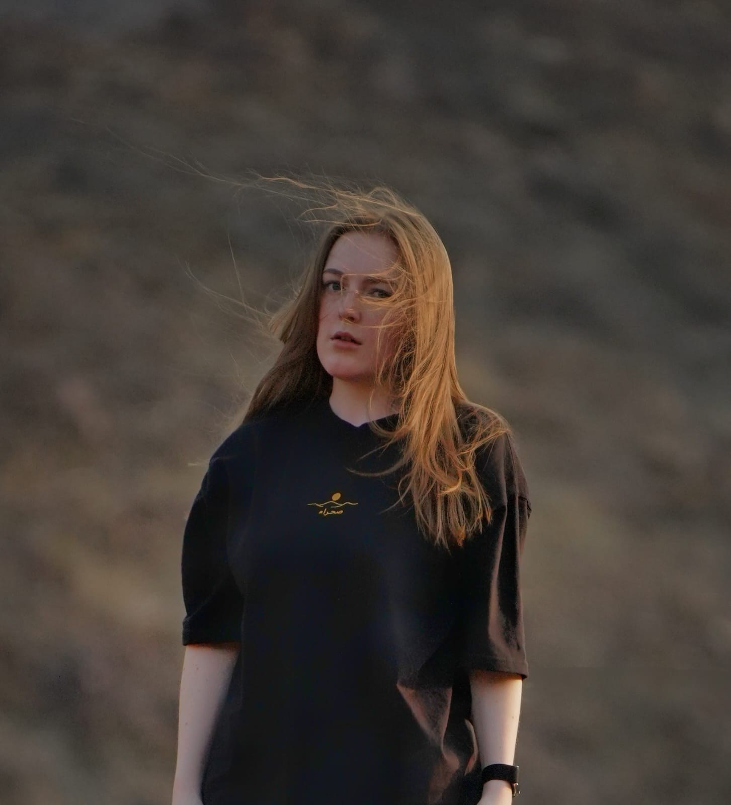 The Al Quaa Galaxy tee worn in the Hajar mountains — the embroidered mark on the chest. Female model wears M in the Oversized fit.