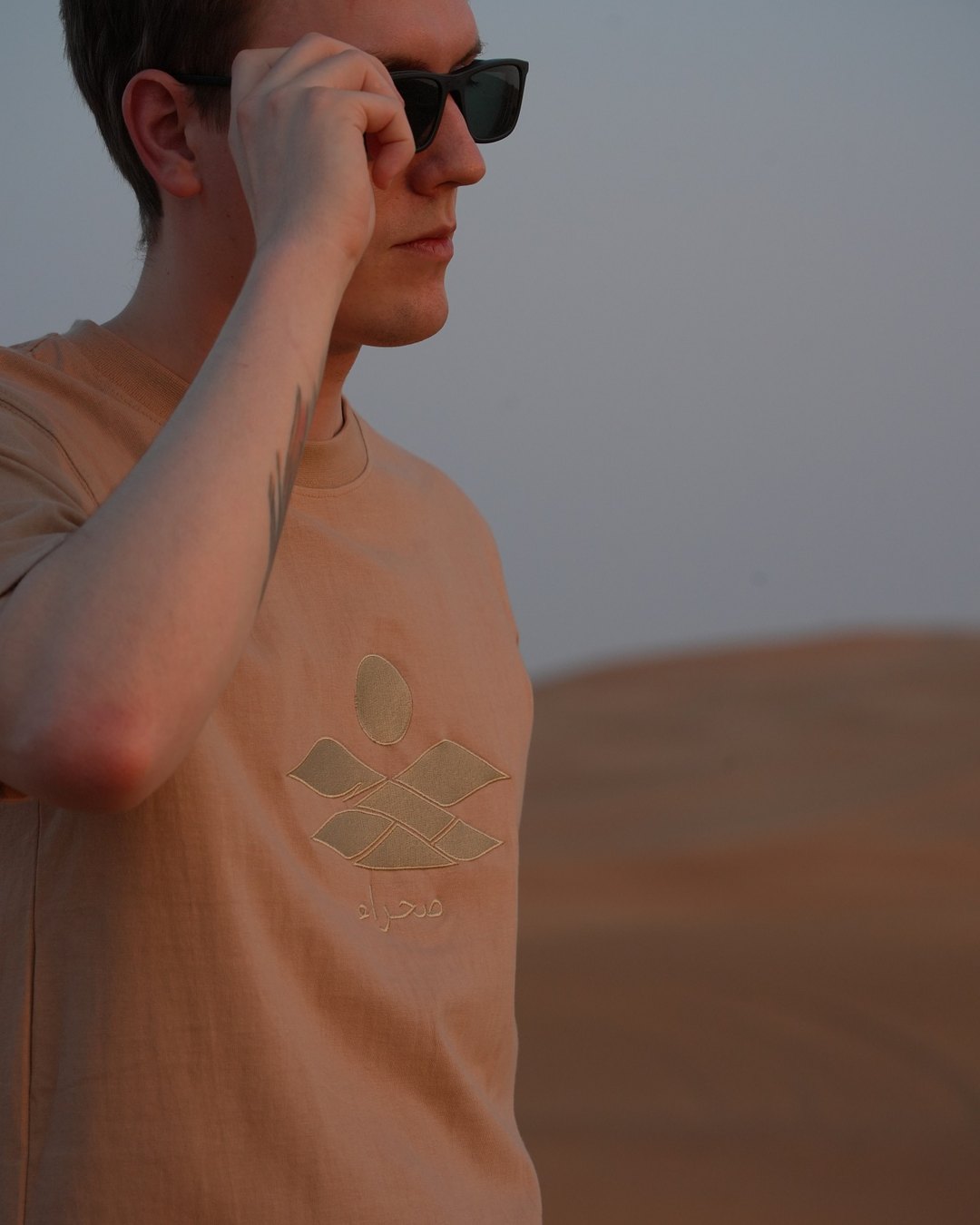 The Empty Quarter tee, the embroidered chest at an angle — thread on thread, sand on sand