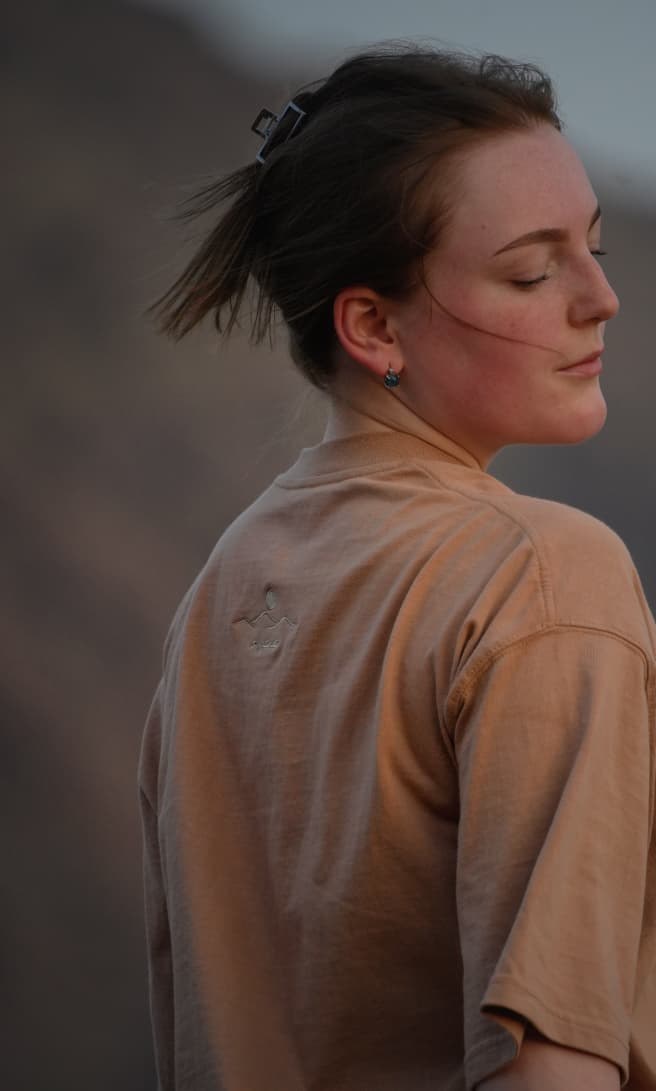 The Empty Quarter tee in profile as the light drops over the mountains. Female model wears M in the Oversized fit.