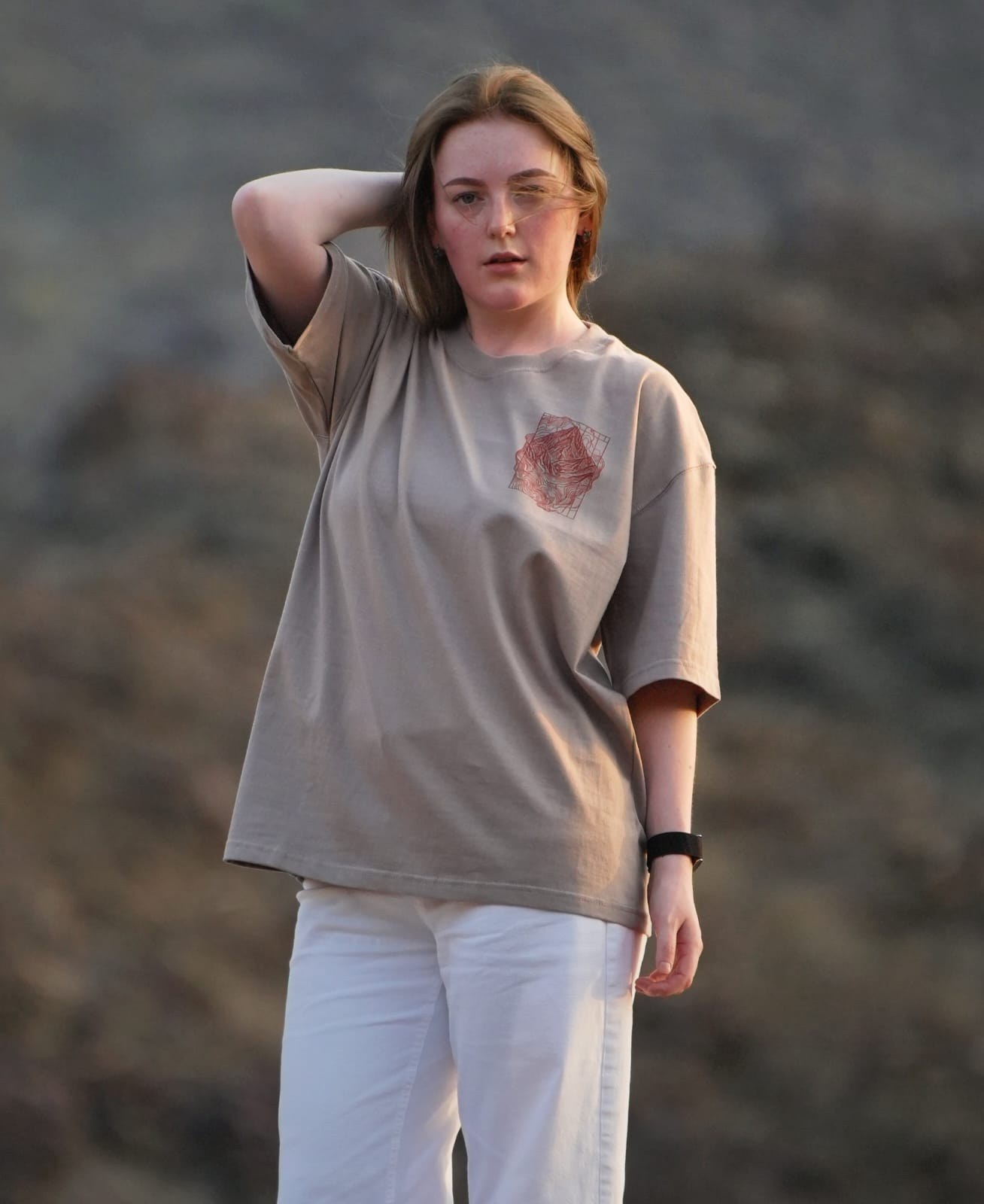 The Hajar Mountains tee worn in the Hajar themselves — the contour-line mountain mark on the chest. Female model wears M in the Oversized fit.