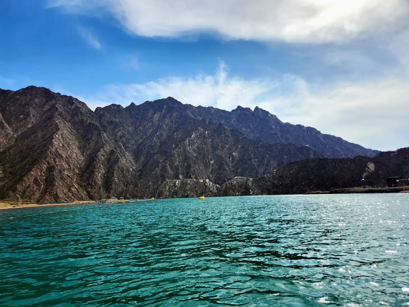 Hatta Dam's turquoise reservoir with the bare Hajar Mountains rising behind it, Dubai, UAE.
