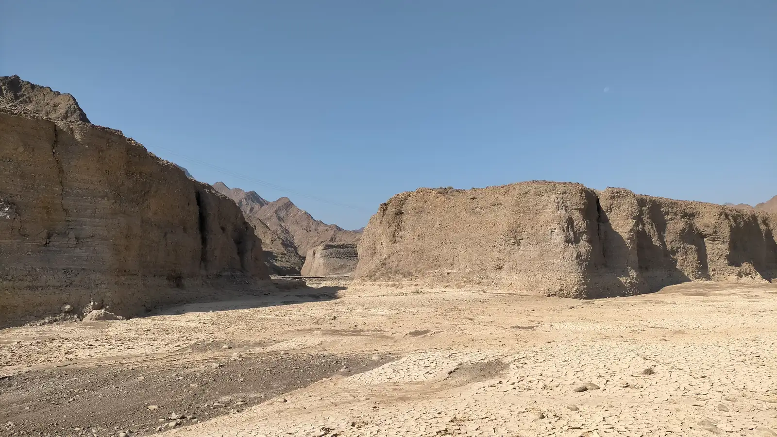 Dry gravel bed and eroded banks of a tributary in Wadi Wurayah, Fujairah, under the Hajar Mountains